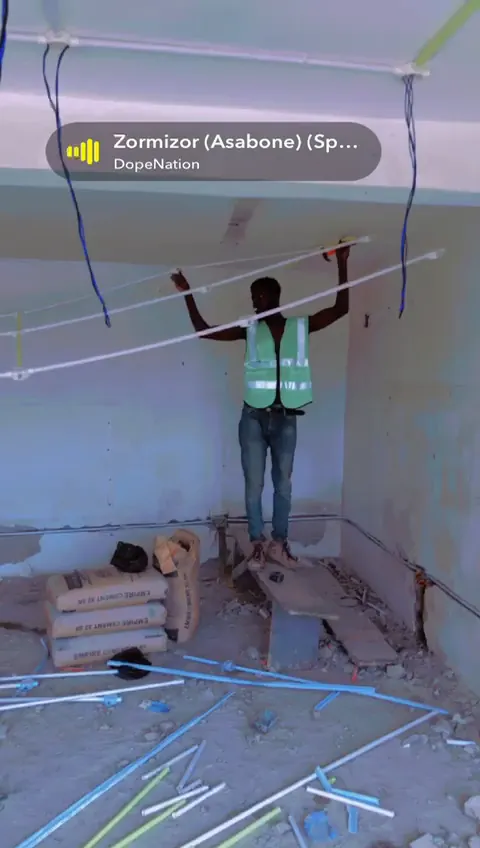 Technician preparing ceiling wiring in a corporate interior space